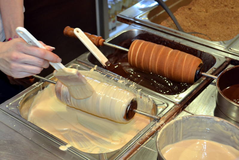 White chocolate being applied to a piping hot chimney cake